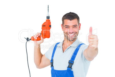 Smiling repairman with drill machine gesturing thumbs up