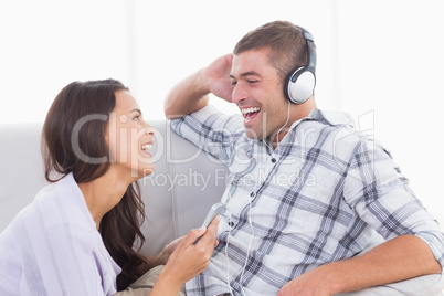 Woman holding mobile phone while man listening music