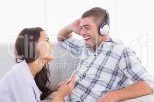 Woman holding mobile phone while man listening music