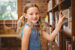 Cute little girl selecting book in library