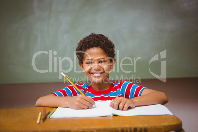 Little boy writing book in classroom