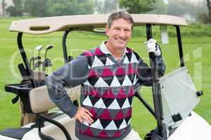 Happy golfer beside his golf buggy