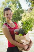 Fit woman holding bag of healthy groceries