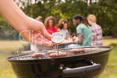 Man using meat thermometer while barbecuing