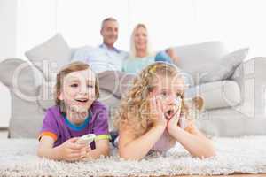 Children watching TV while parents sitting on sofa
