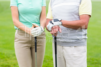 Golfing couple holding clubs