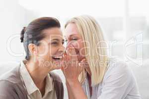 Woman revealing secret to her friend smiling