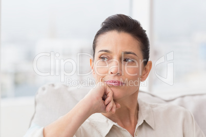 Thoughtful woman sitting on sofa