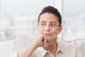 Thoughtful woman sitting on sofa