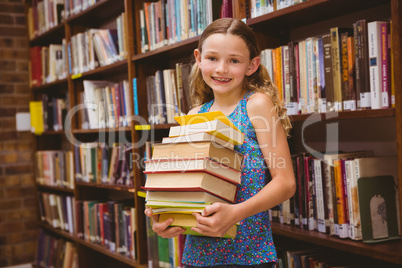 Cute little girl carrying books in library