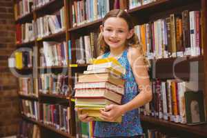 Cute little girl carrying books in library