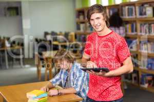 Male college student using digital tablet in library