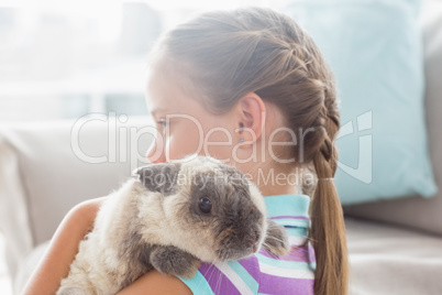 Girl holding rabbit at home