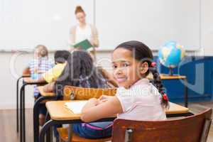 Cute pupil smiling at camera in classroom