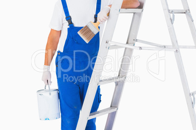 Handyman with paintbrush and can on ladder