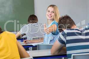 Beautiful female student gesturing thumbs up in class
