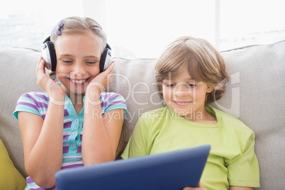 Boy playing music on laptop for sister at home