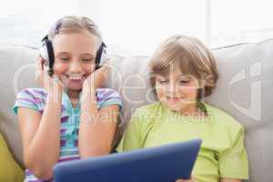 Boy playing music on laptop for sister at home