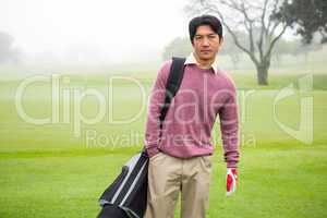 Golfer standing holding his golf bag