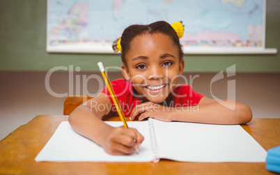 Little girl writing book in classroom