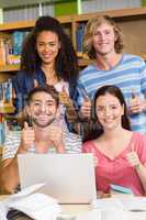 College students gesturing thumbs up in library