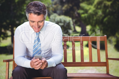 Businessman using his phone in the park