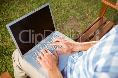 Man sitting on park bench using laptop