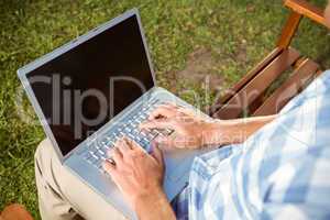 Man sitting on park bench using laptop