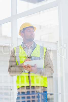 Architect in reflective clothing writing on clipboard at office