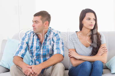 Couple looking away while sitting on sofa