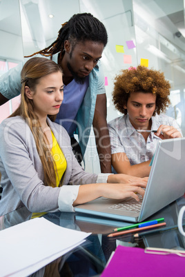 Creative business people using laptop at desk