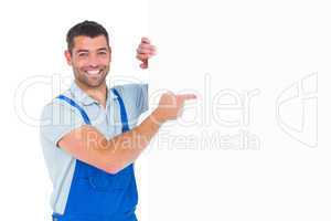 Repairman in overalls pointing at placard