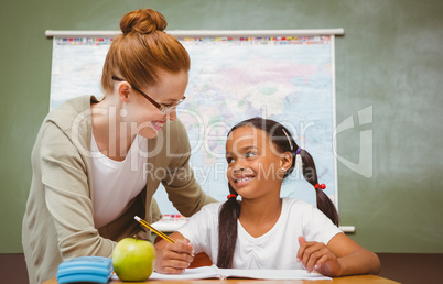 Teacher assisting girl with homework in classroom