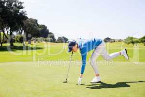 Female golfer picking up golf ball