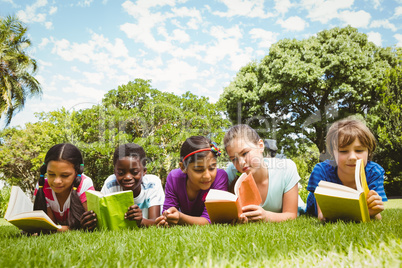 Children lying on grass and reading books