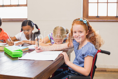 Cute pupils writing at desk in classroom