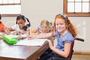 Cute pupils writing at desk in classroom