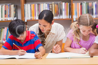 Pretty teacher helping pupils in library Pretty teacher helping pupils in library