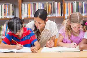 Pretty teacher helping pupils in library