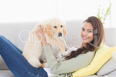 Woman playing with puppy on sofa at home