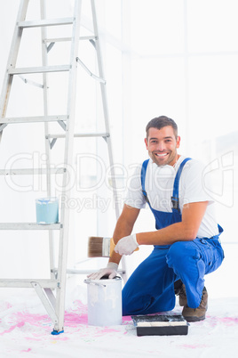 Smiling handyman with paintbrush and can at home