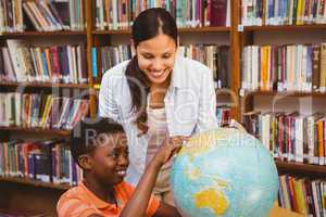 Teacher and boy looking at globe in library