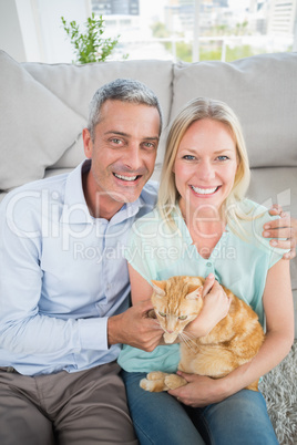 Happy couple with cat sitting in living room