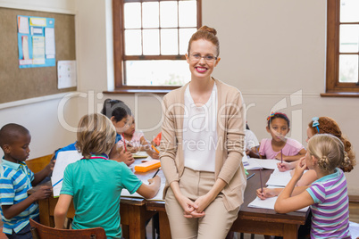 Pretty teacher smiling at camera with arms crossed