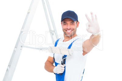 Happy handyman with paint roller gesturing okay