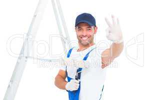 Happy handyman with paint roller gesturing okay