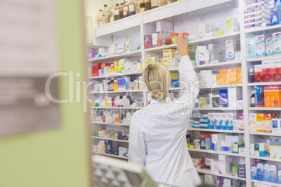 Rear view of student taking medicine from shelf