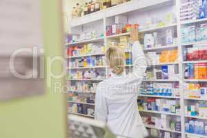 Rear view of student taking medicine from shelf