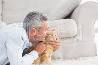 Man kissing cat by sofa at home