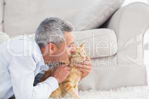 Man kissing cat by sofa at home